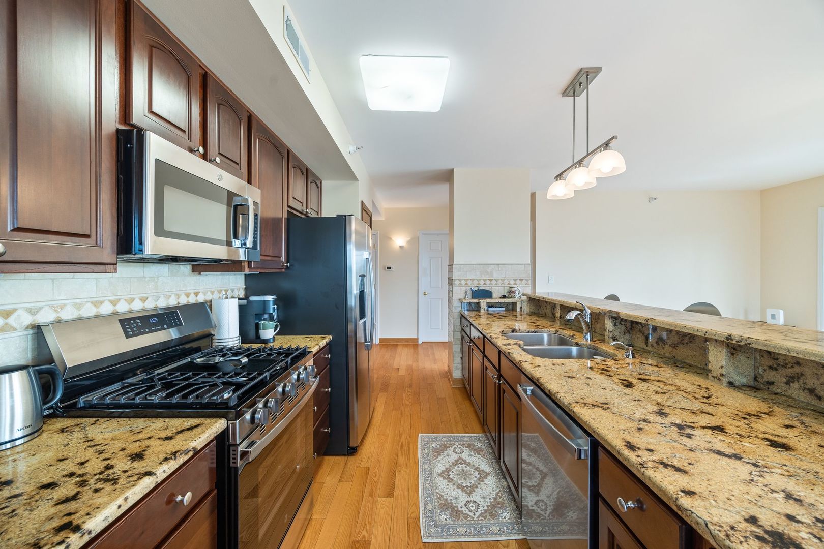 77 North Wolf Road, Unit 309 Northlake, IL 60164 - Photo 13 of 25 a kitchen with stainless steel appliances granite countertop a stove a sink dishwasher and microwave oven with large wooden cabinets