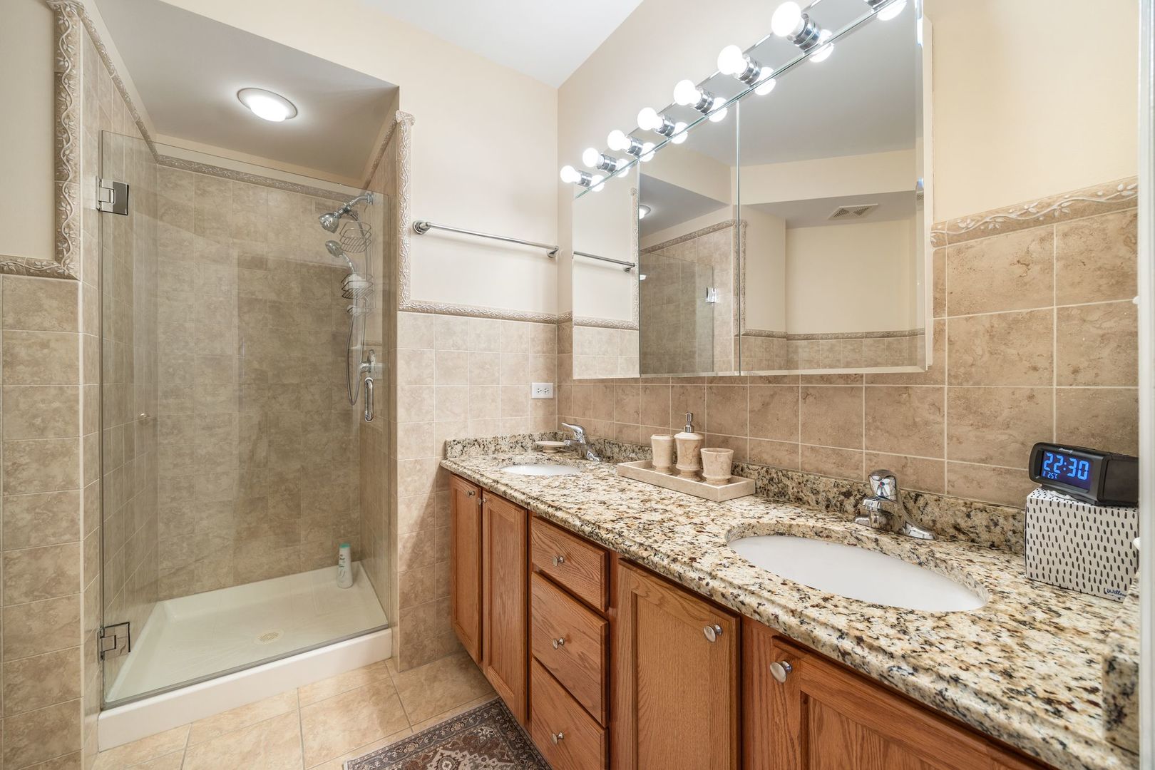 77 North Wolf Road, Unit 309 Northlake, IL 60164 - Photo 18 of 25 a bathroom with a granite countertop sink a large mirror and shower