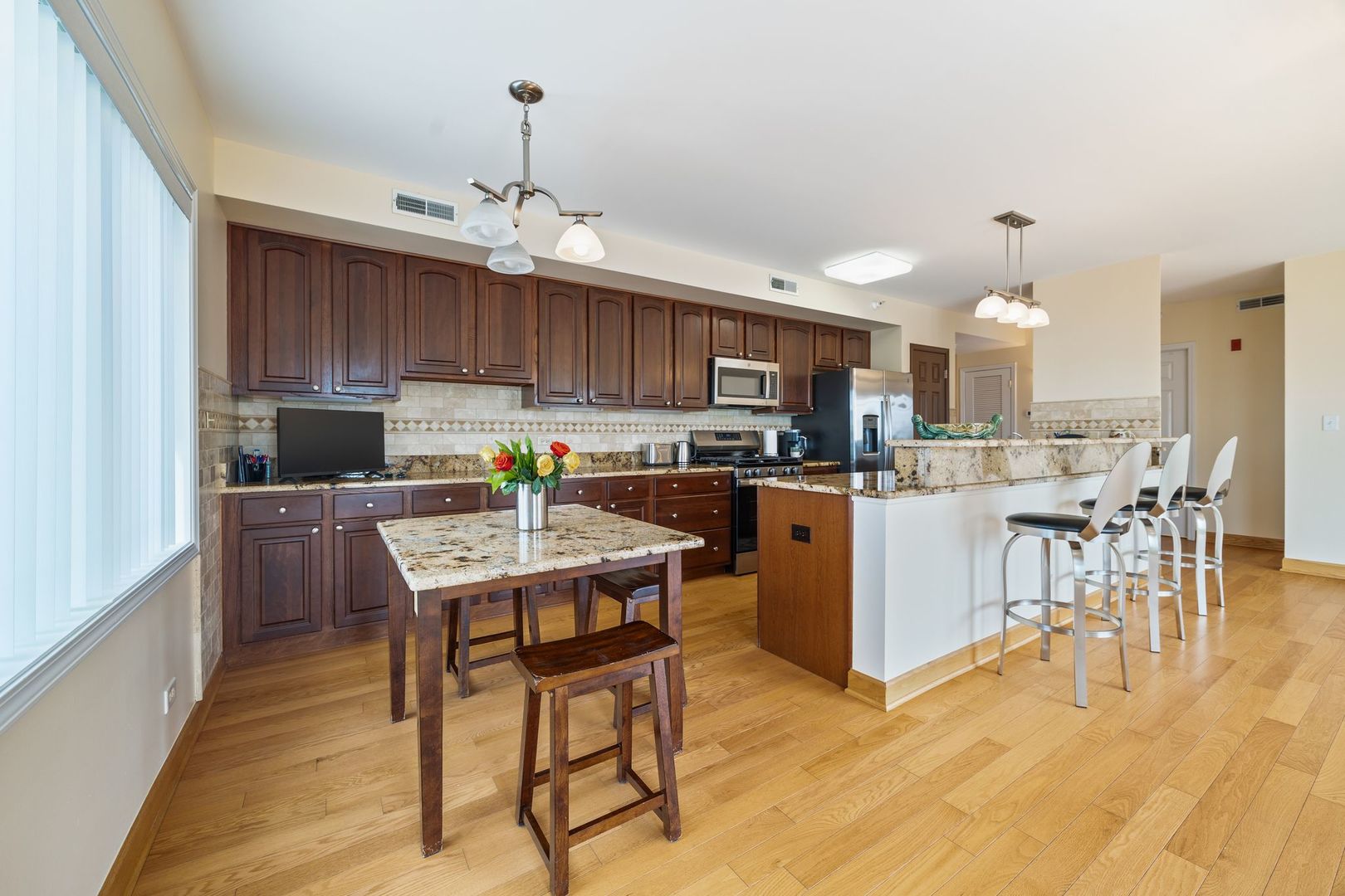 77 North Wolf Road, Unit 309 Northlake, IL 60164 - Photo 10 of 25 a living room with stainless steel appliances kitchen island granite countertop a dining table chairs refrigerator and a microwave