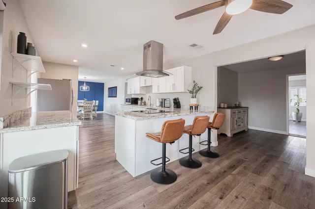 a kitchen with stainless steel appliances granite countertop a table chairs sink and cabinets