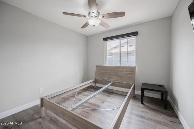 a room with a flat screen tv and a ceiling fan