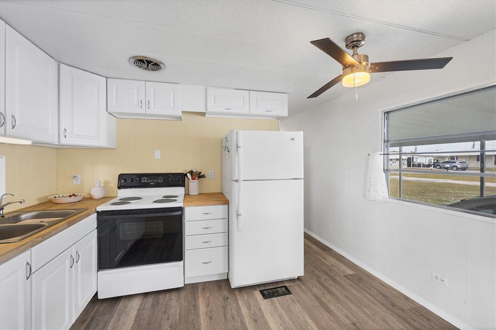 4114 10th St Court East Ellenton, FL 34222 - Photo 13 of 44 a kitchen with a stove a refrigerator and a white cabinets