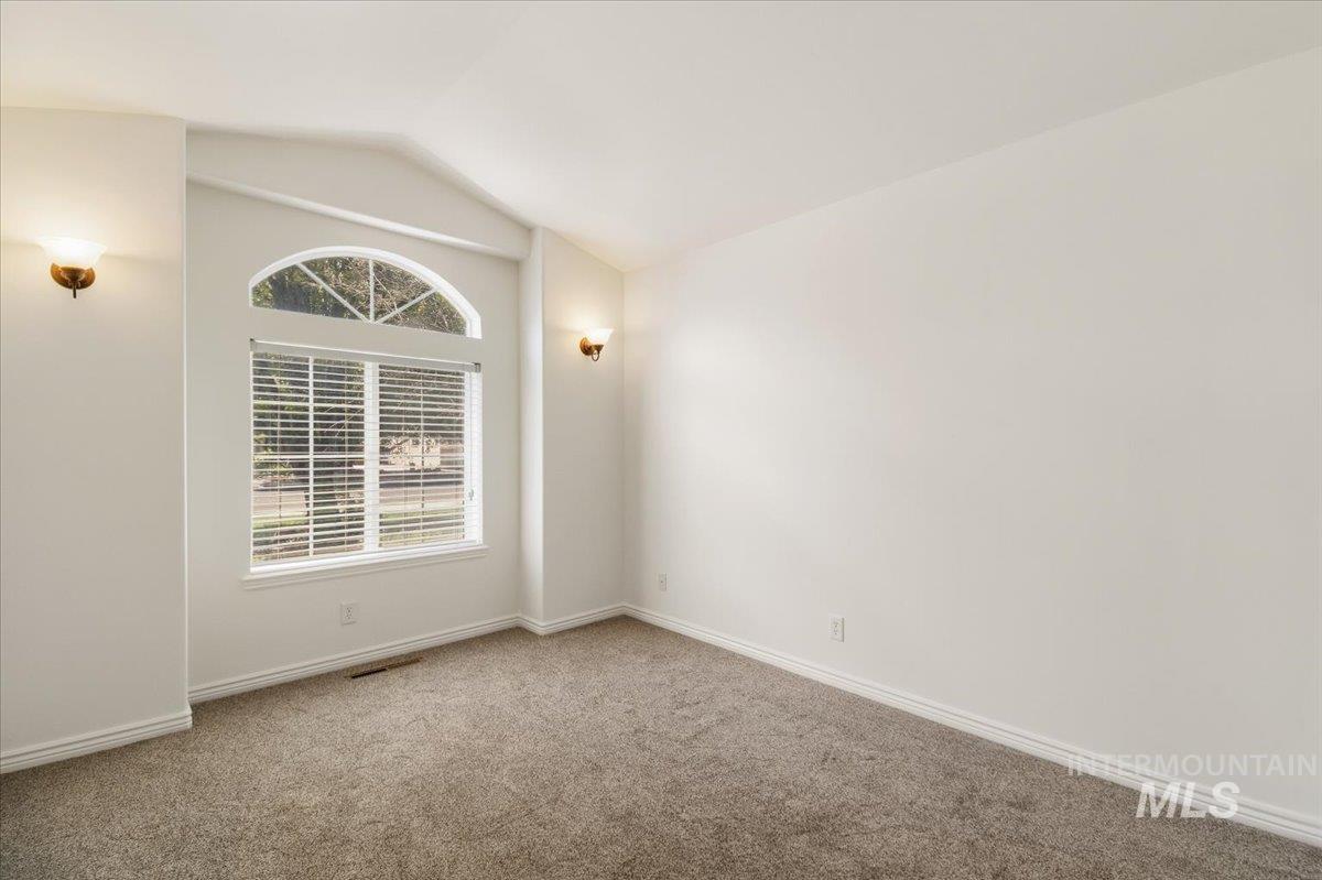 2032 Talus Loop Twin Falls, ID 83301 - Photo 22 of 43 Vaulted ceiling room featuring a large arched window with blinds, sconce lighting, and wall-to-wall carpeting
