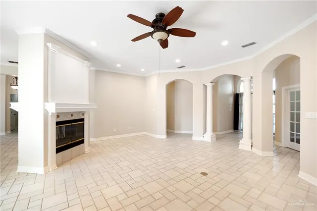 a view of a livingroom with a fireplace a ceiling fan and windows