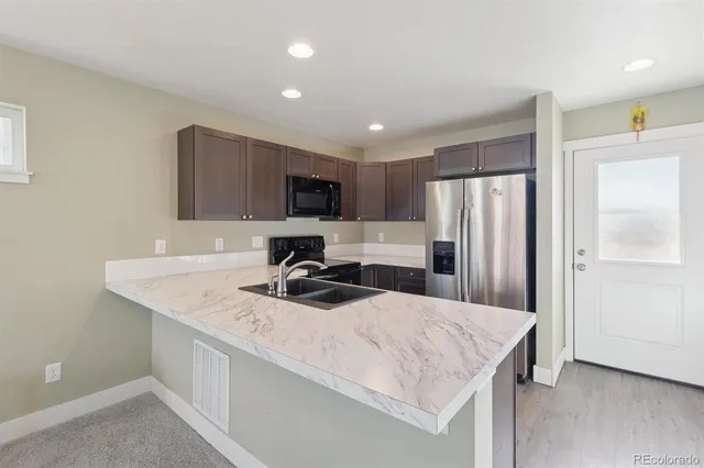 a kitchen with stainless steel appliances granite countertop a sink a refrigerator a stove a microwave a refrigerator and white cabinets with wooden floor