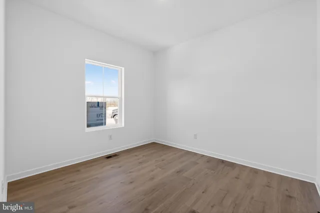 a view of an empty room with wooden floor and closet