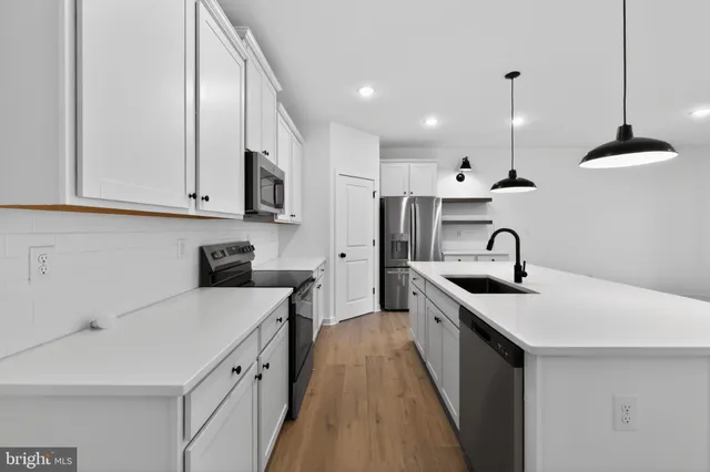 a view of kitchen with kitchen island a sink stainless steel appliances and cabinets