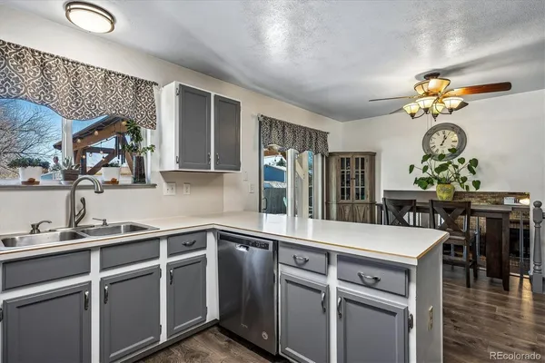 a kitchen with a sink a stove and chairs with wooden floor