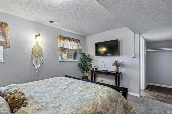 a bedroom with a bed and a flat tv screen on dresser