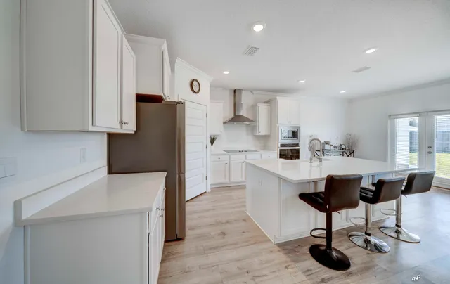 a kitchen with stainless steel appliances granite countertop a refrigerator a sink a stove a dining table and chairs