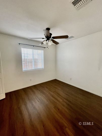 1304 South McCall Street Ridgecrest, CA 93555 - Photo 13 of 22 an empty room with wooden floor fan and windows