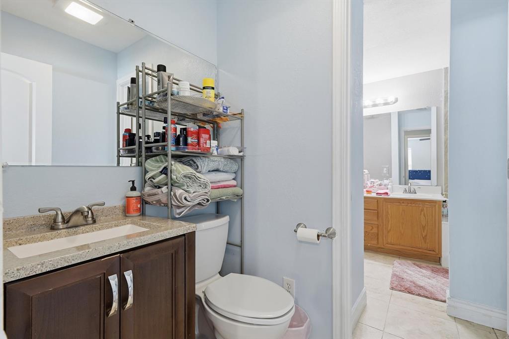 114 Drake Lane Garland, TX 75043 - Photo 15 of 27 a bathroom with a granite countertop sink vanity mirror and toilet