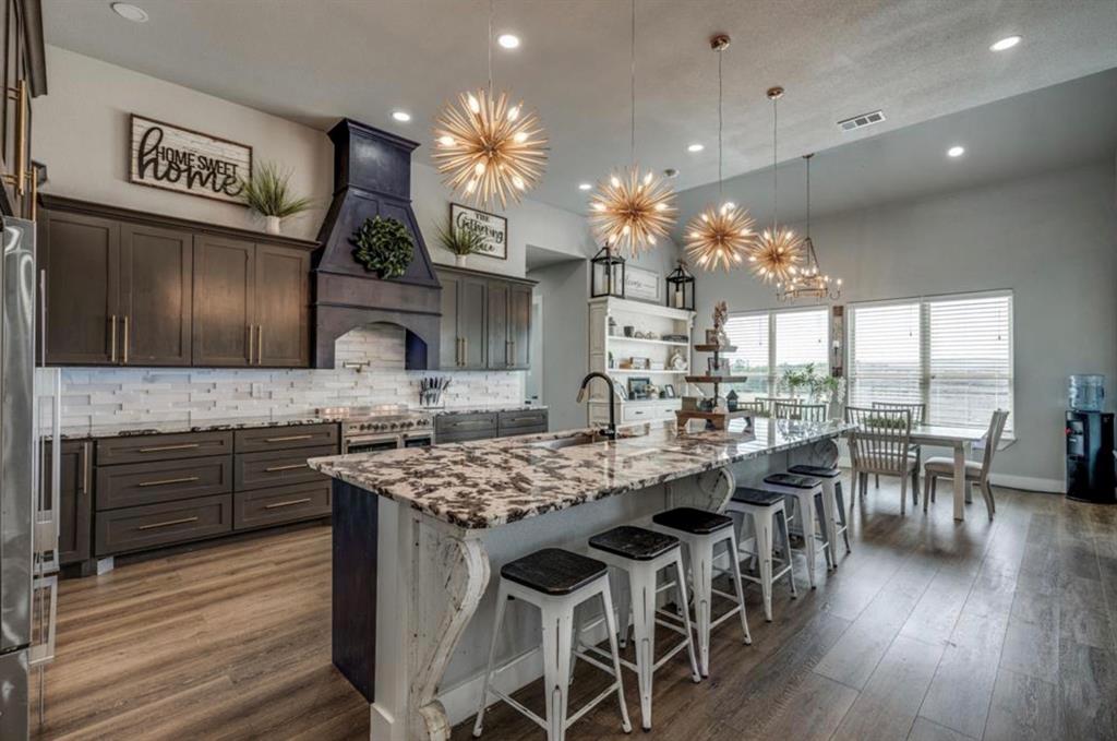 997 Ovilla Road Waxahachie, TX 75167 - Photo 1 of 32 Spacious kitchen featuring an expansive island with stone countertop, dark cabinetry, and wood-finish flooring