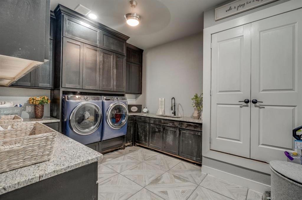 997 Ovilla Road Waxahachie, TX 75167 - Photo 19 of 32 Laundry room featuring dark wood cabinetry, light speckled countertops, a utility sink with a matte black faucet, and white paneled double doors