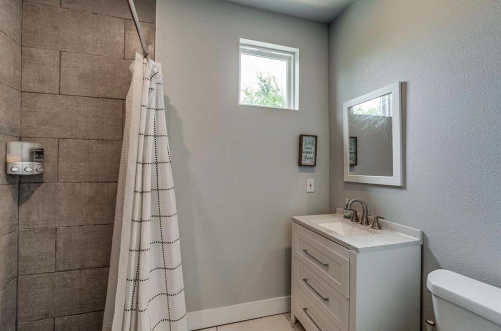 997 Ovilla Road Waxahachie, TX 75167 - Photo 20 of 32 Full bathroom featuring a shower with large format tile surround, a single vanity with a solid surface countertop, white cabinetry with drawer storage, and a framed mirror