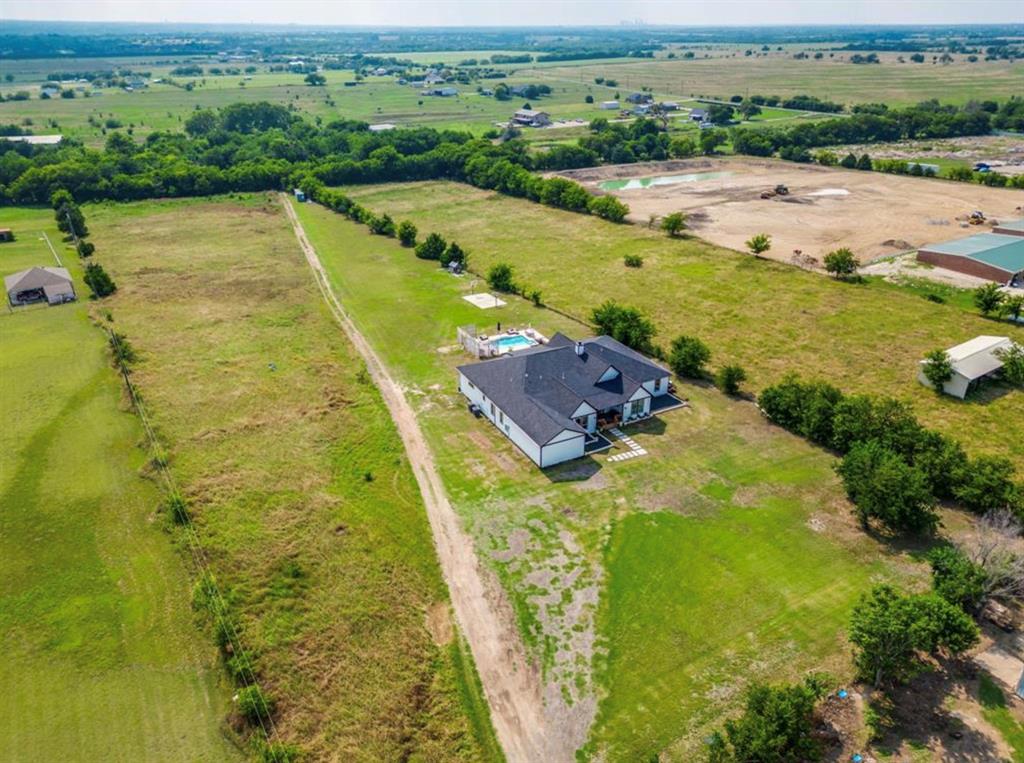 997 Ovilla Road Waxahachie, TX 75167 - Photo 2 of 32 White-exterior residence featuring a dark roof, a backyard pool, and expansive green grounds with scattered trees