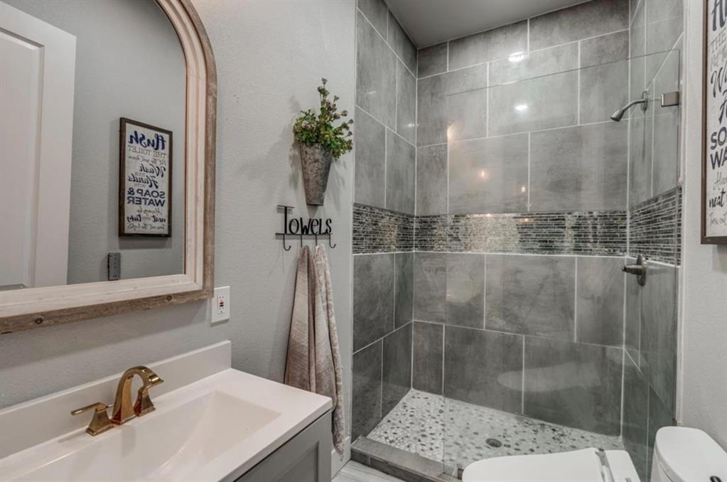997 Ovilla Road Waxahachie, TX 75167 - Photo 25 of 32 Bathroom featuring a glass-enclosed shower with gray large-format tile walls and a mosaic accent band