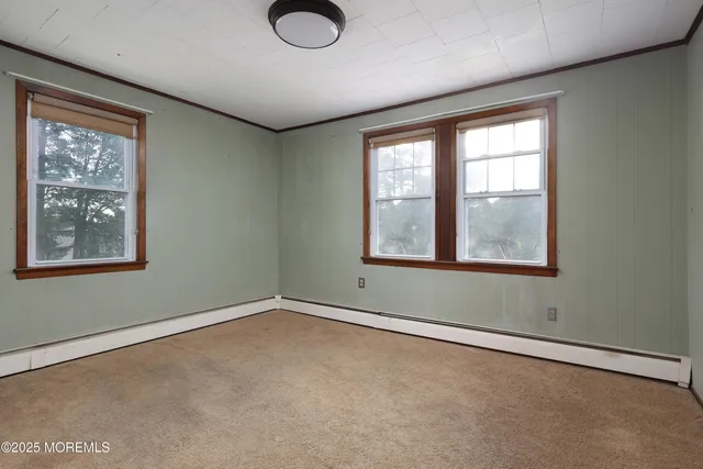 an empty room with chandelier fan and windows