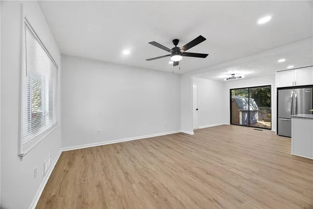 a view of an empty room with a window and wooden floor
