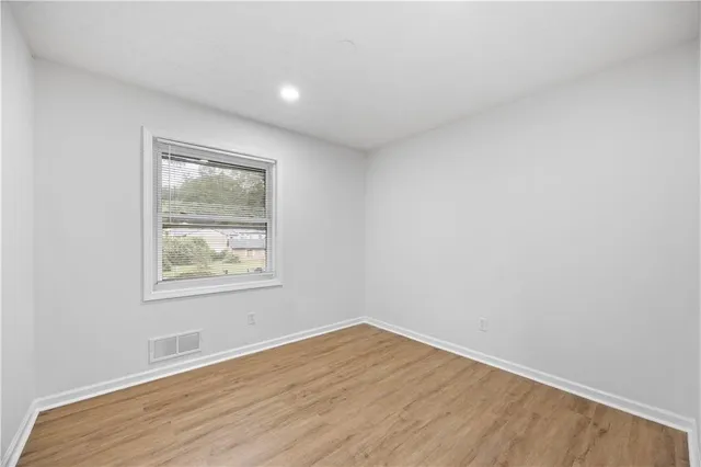 an empty room with wooden floor and a window