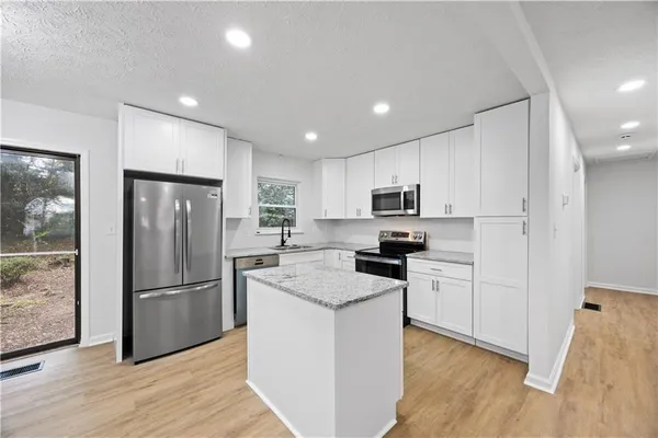 a kitchen with stainless steel appliances granite countertop a refrigerator microwave and stove top oven