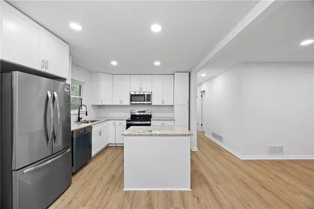 a kitchen with stainless steel appliances a refrigerator sink and microwave