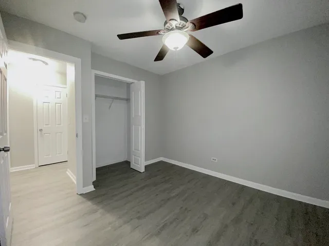 an empty room with wooden floor fan and windows