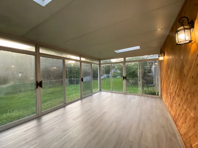 a view of empty room with wooden floor and floor to ceiling window
