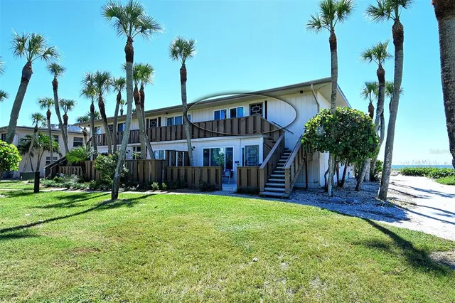 a view of a house with a yard and palm trees