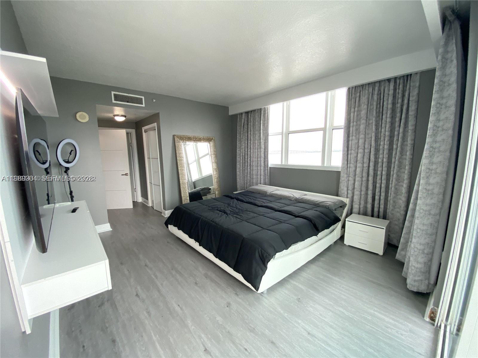 500 Northeast 29th Street, Unit 608 Miami, FL 33137 - Photo 16 of 36 a bedroom with a bed a mirror and a window