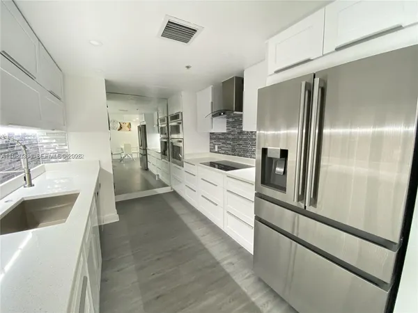 a large white kitchen with a sink stainless steel appliances and cabinets