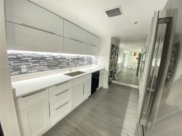 a view of a kitchen with stainless steel appliances wooden floor and staircase