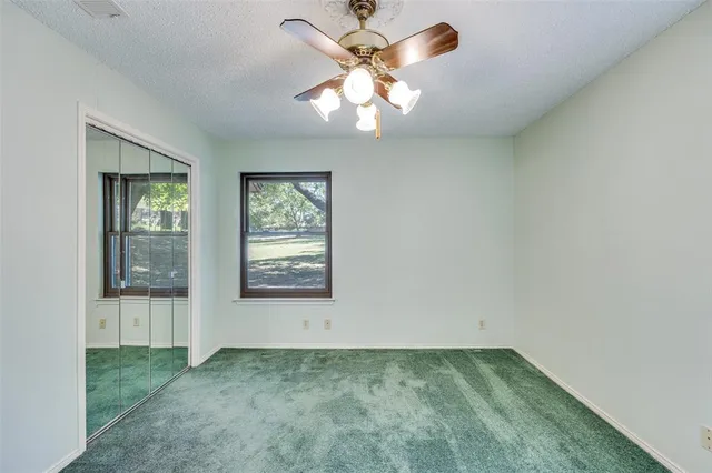 an empty room with windows and fan