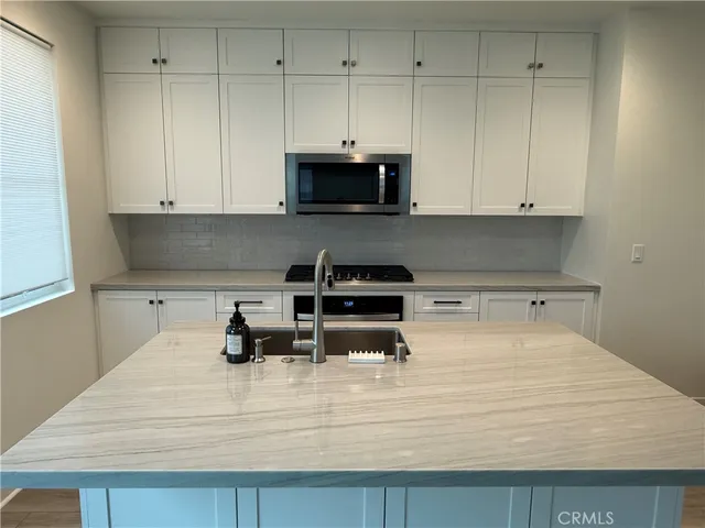 a kitchen with granite countertop white cabinets and stainless steel appliances