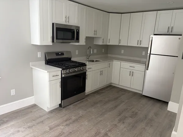 a kitchen with granite countertop cabinets stainless steel appliances and a wooden floor