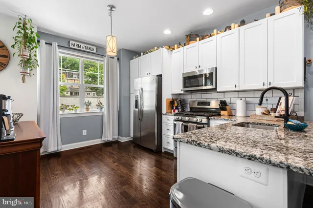 a kitchen with stainless steel appliances granite countertop a refrigerator oven a sink dishwasher and white cabinets with wooden floor