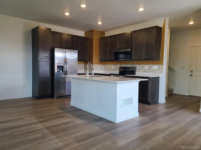 a kitchen with stainless steel appliances granite countertop a stove a sink and a refrigerator