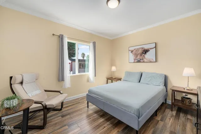 a bedroom with a bed a chair and potted plant on the table