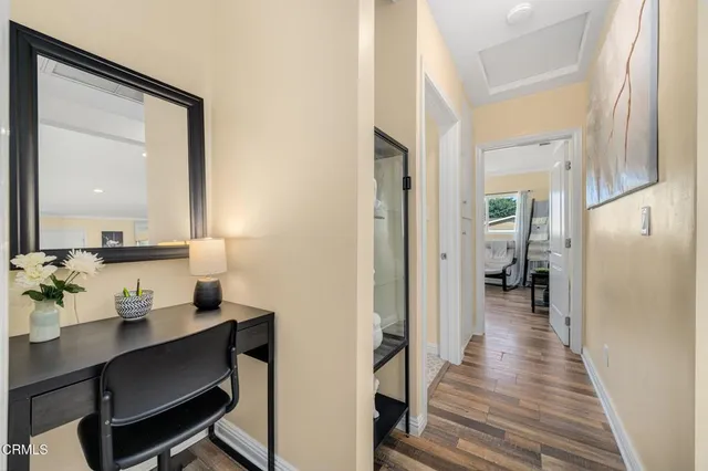 a view of a hallway with view of living room with wooden floor