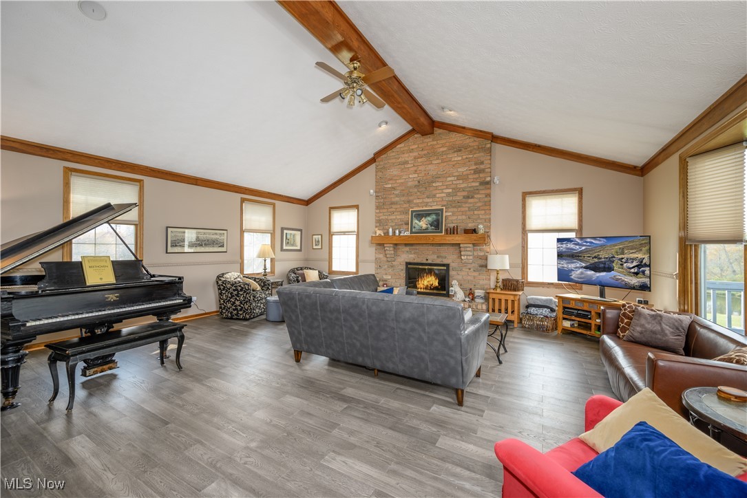 7300 Darrow Road Hudson, OH 44236 - Photo 11 of 44 Living room with vaulted ceiling with beams, a fireplace, ceiling fan, hardwood / wood-style flooring, and ornamental molding
