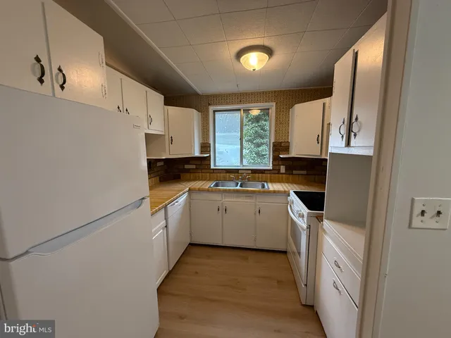 a kitchen with a sink a stove top oven and white cabinets