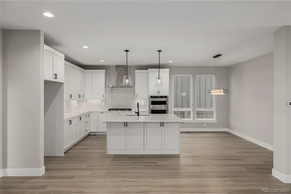 a large kitchen with stainless steel appliances a large counter top and a refrigerator
