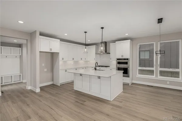 a large kitchen with stainless steel appliances a large counter top a sink cabinets and wooden floor