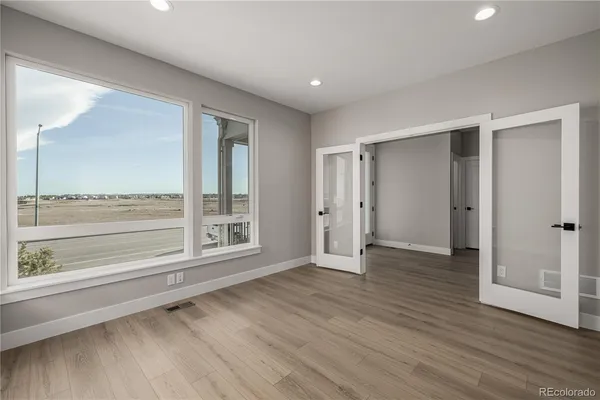 a view of an empty room with wooden floor and a window