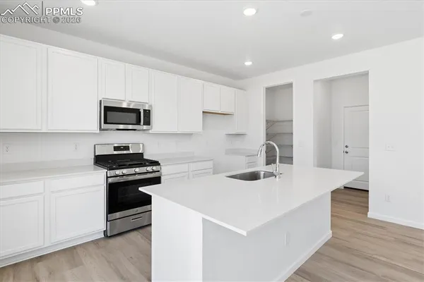 a kitchen with stainless steel appliances a stove a sink a microwave and cabinets