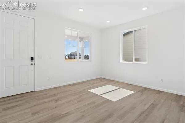 an empty room with wooden floor and windows
