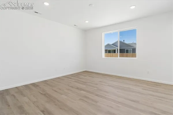 an empty room with wooden floor and windows