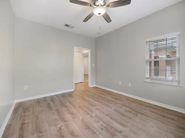 a view of an empty room with wooden floor and a window
