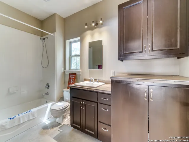 a bathroom with a granite countertop sink a toilet a mirror and shower