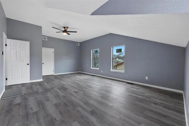 a view of an empty room with window and wooden floor